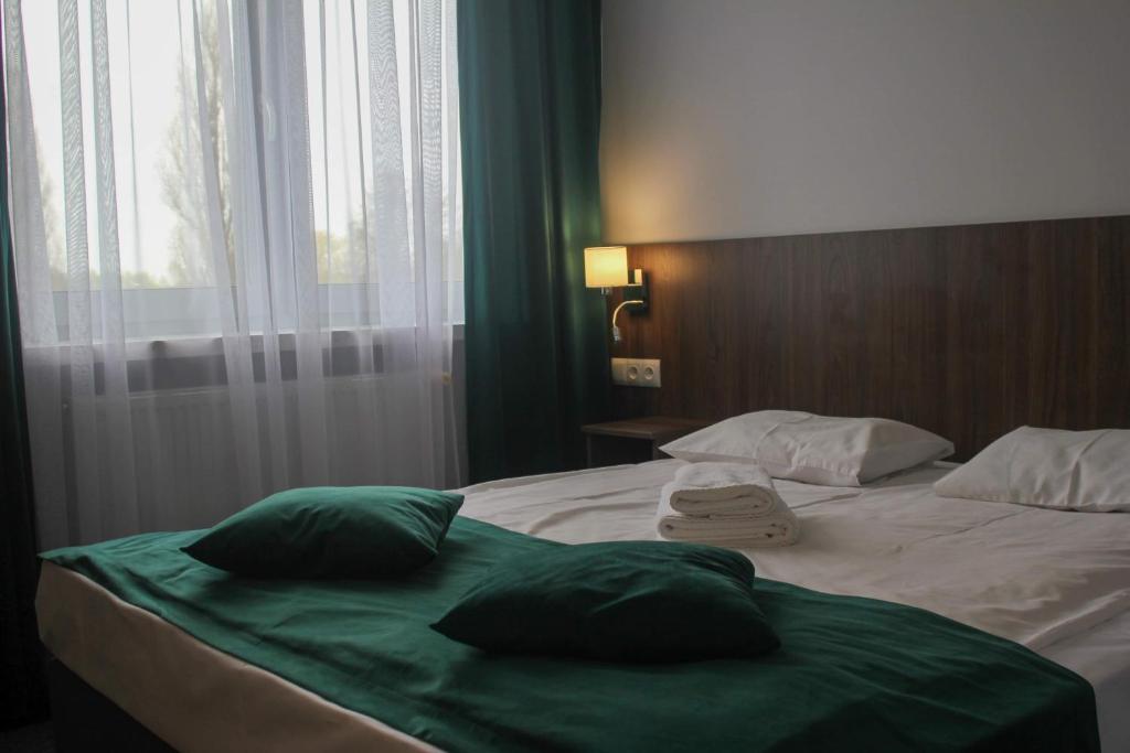 uma cama com duas almofadas verdes com uma janela em Eurohotel em Baniocha