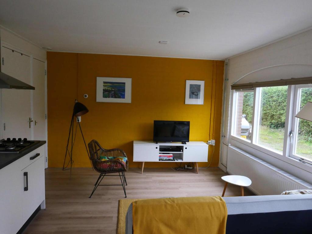 a living room with a tv and a yellow wall at Wadnhûs in Kollum