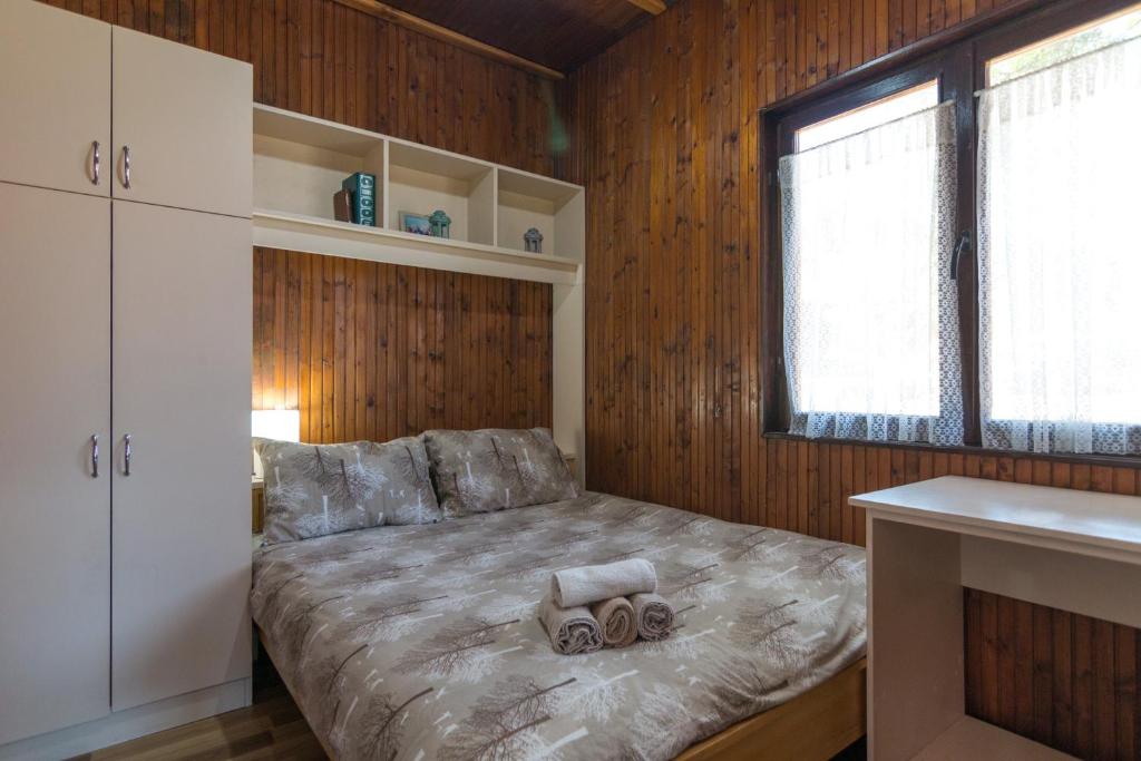 a bedroom with a bed with wooden walls and a window at Bogu iza nogu 1 in Rastište