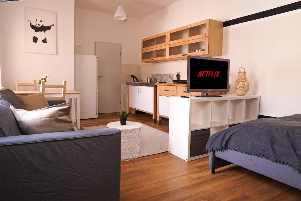 een woonkamer met een bank en een keuken bij FULL HOUSE Studios - Panda Apartment - WiFi inkl in Halle an der Saale