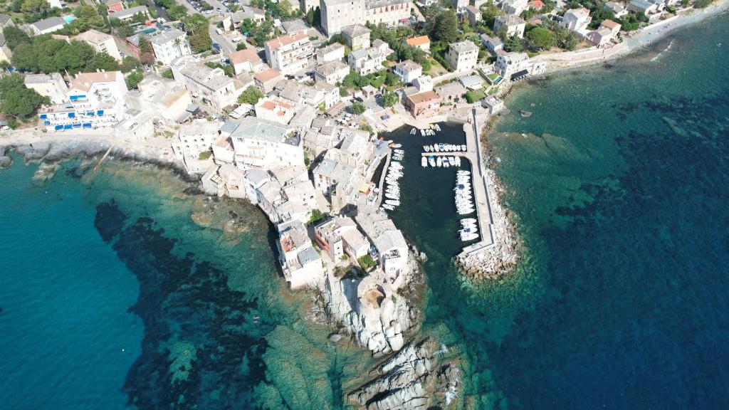 Une grande terrasse sur la mer في Brando: اطلالة جوية على جزيرة صغيرة في المحيط