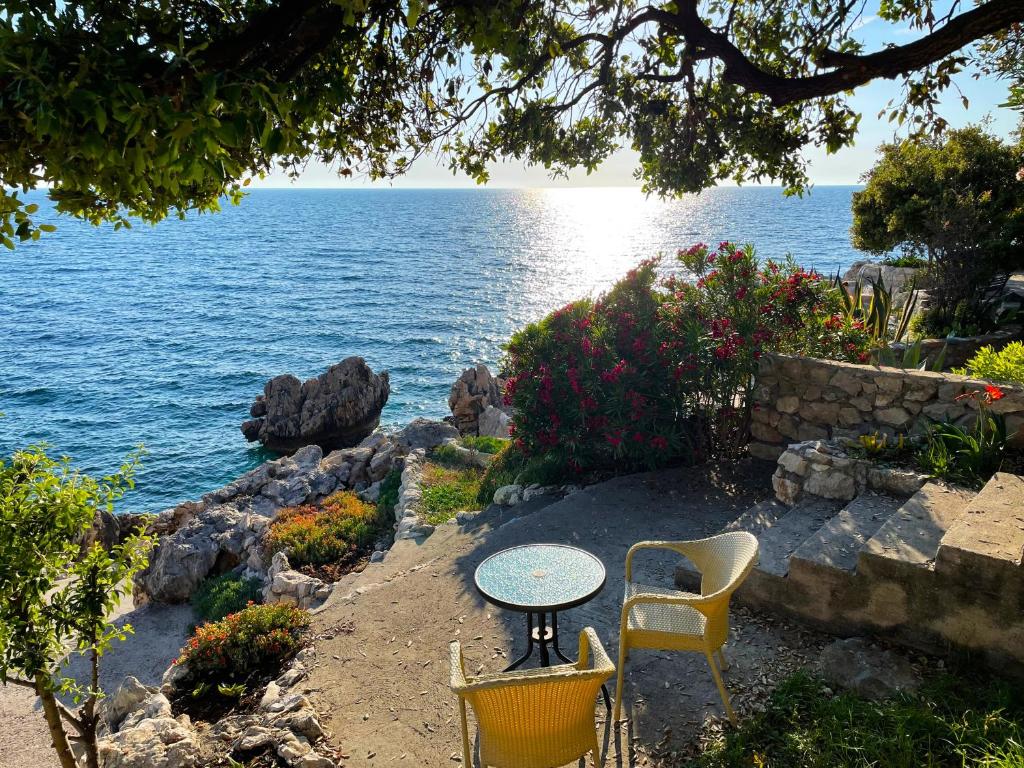 stół i krzesła siedzące obok wody w obiekcie Luxury Seaside Holm Oak Villa with Private Beach w Barze