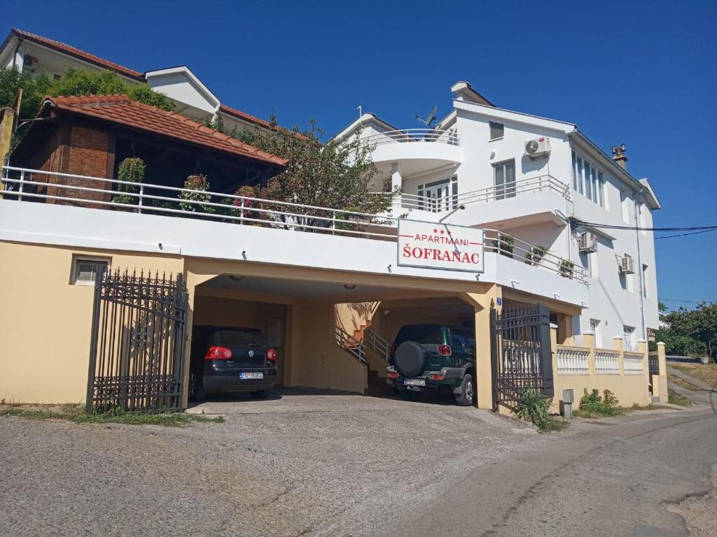 un grand bâtiment blanc avec un garage pour voitures dans l'établissement Apartments Šofranac, à Podgorica