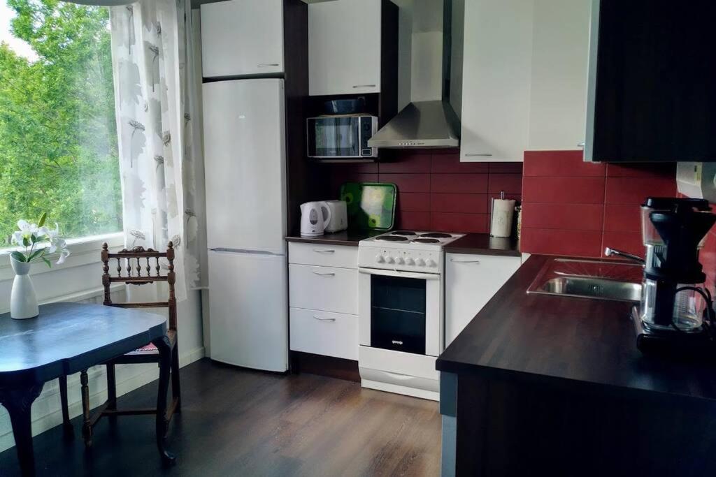 cocina con electrodomésticos blancos, mesa y ventana en Apartment with two bedrooms and a parking space en Vantaa