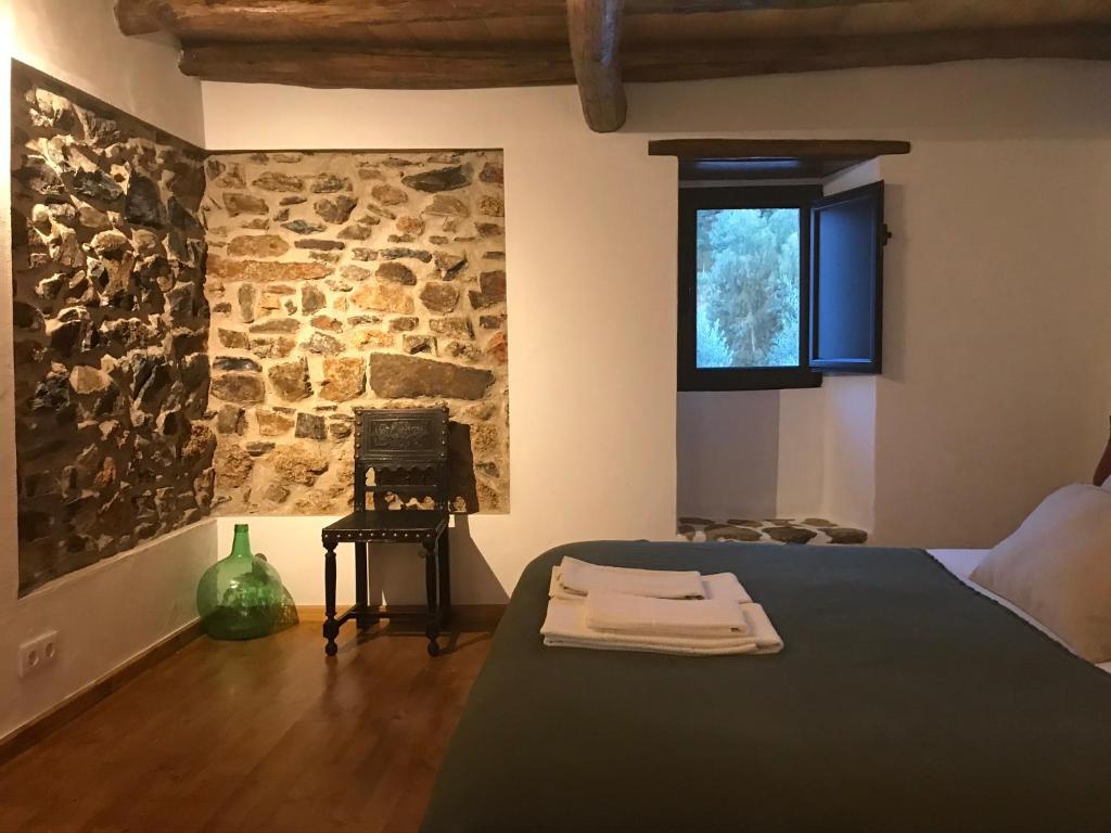 - une chambre avec un lit et un mur en pierre dans l'établissement Azeite de Marvão, Olivoturismo casa Venda do Lagar, à Marvão