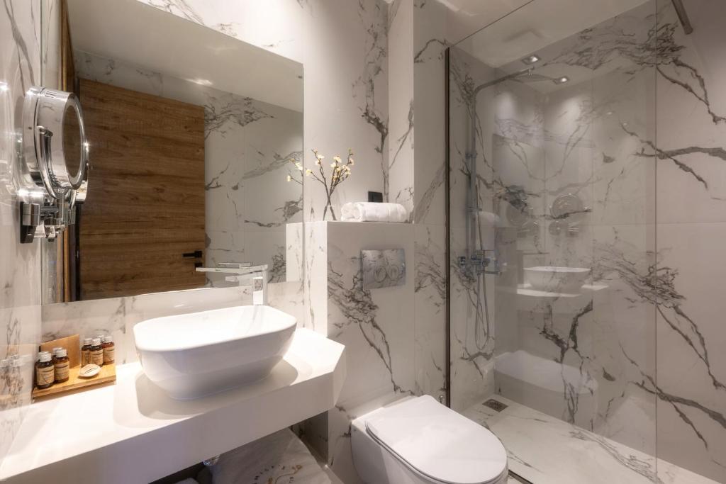 a bathroom with a toilet and a sink and a shower at Emily's Luxury Suites in Pefkochori