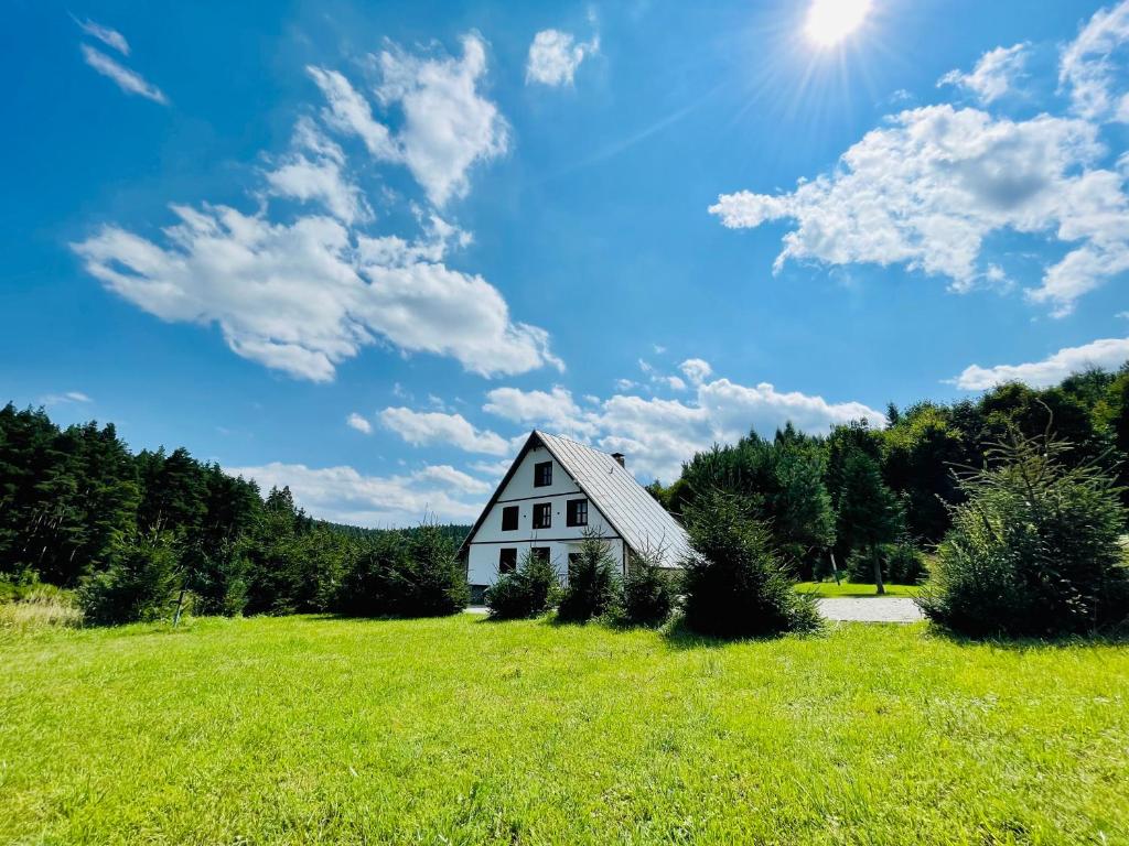 una casa blanca en un campo con el sol en el cielo en Villa Pinus Slovenský raj - Hotel Čingov dependance, en Smižany