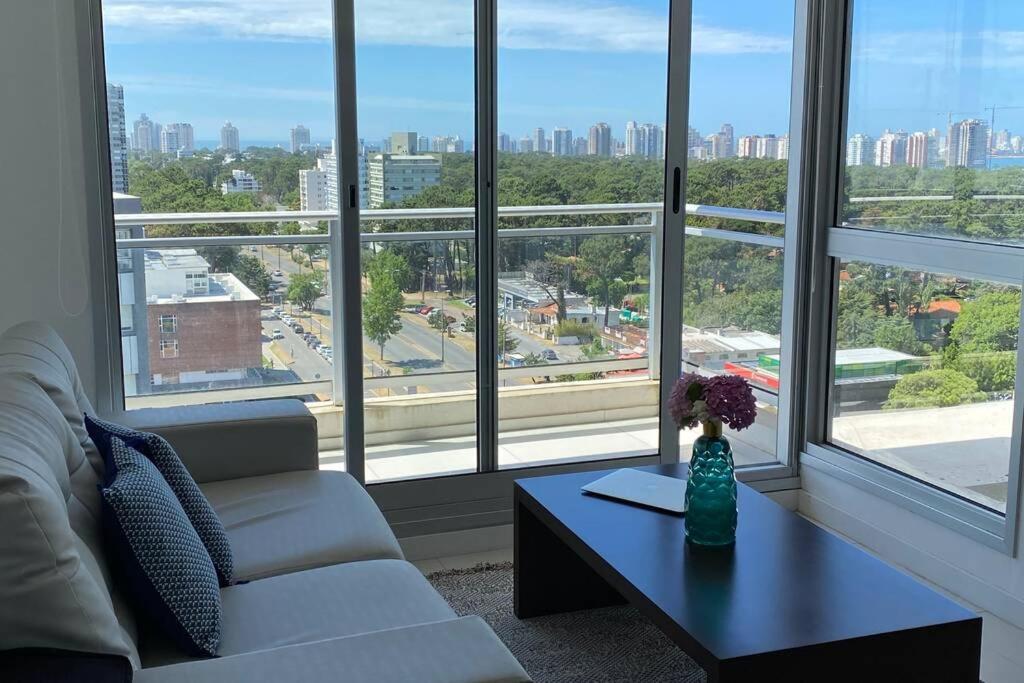 ein Wohnzimmer mit einem Sofa, einem Tisch und Fenstern in der Unterkunft A estrenar, Vista al mar en Torre Bellagio con amenities in Punta del Este