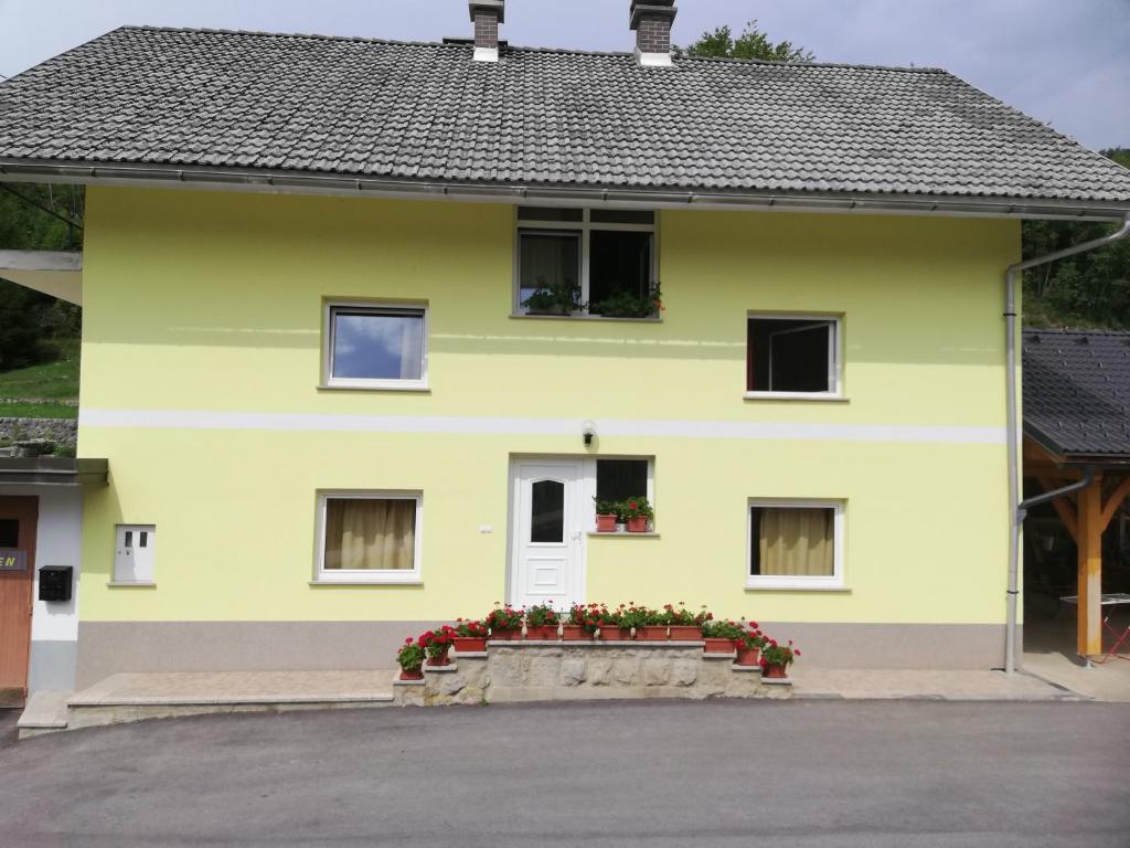 una casa amarilla con flores delante en Apartment Jalen en Bohinjska Bela