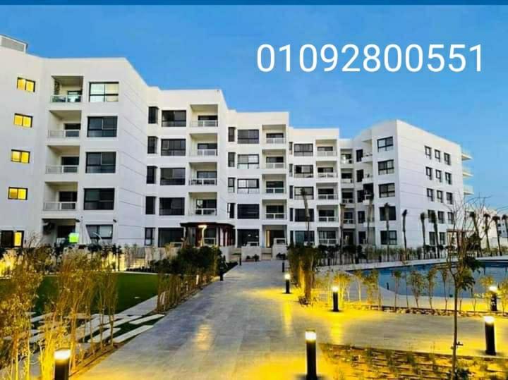 een groot wit appartementencomplex naast een waterlichaam bij شاليه للايجار بورتو سعيد in Port Said