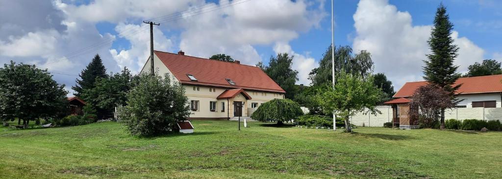 una casa bianca con un tetto rosso su un campo verde di Dom wakacyjny-Czereśniowy Sad a Niemierze