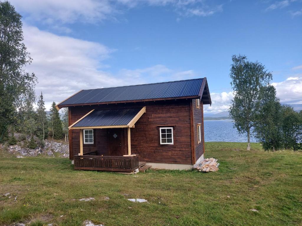 a small house with a solar roof on a field at Villmarksgård, hytte ved vannet in Hattfjelldal