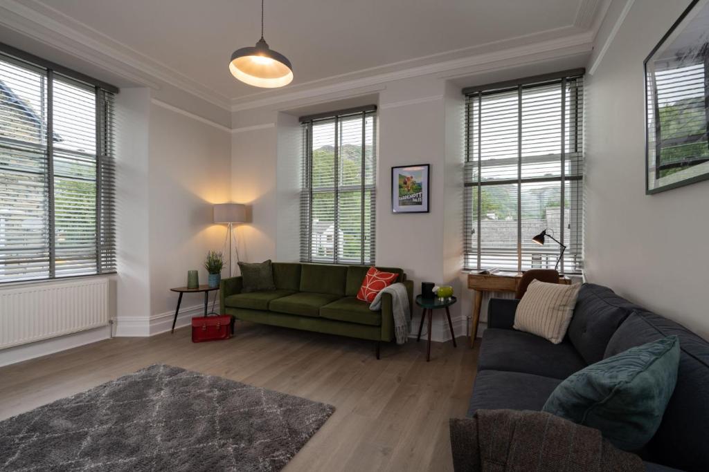 a living room with a green couch and windows at Spacious Apartment in Coniston, by LetMeStay in Coniston