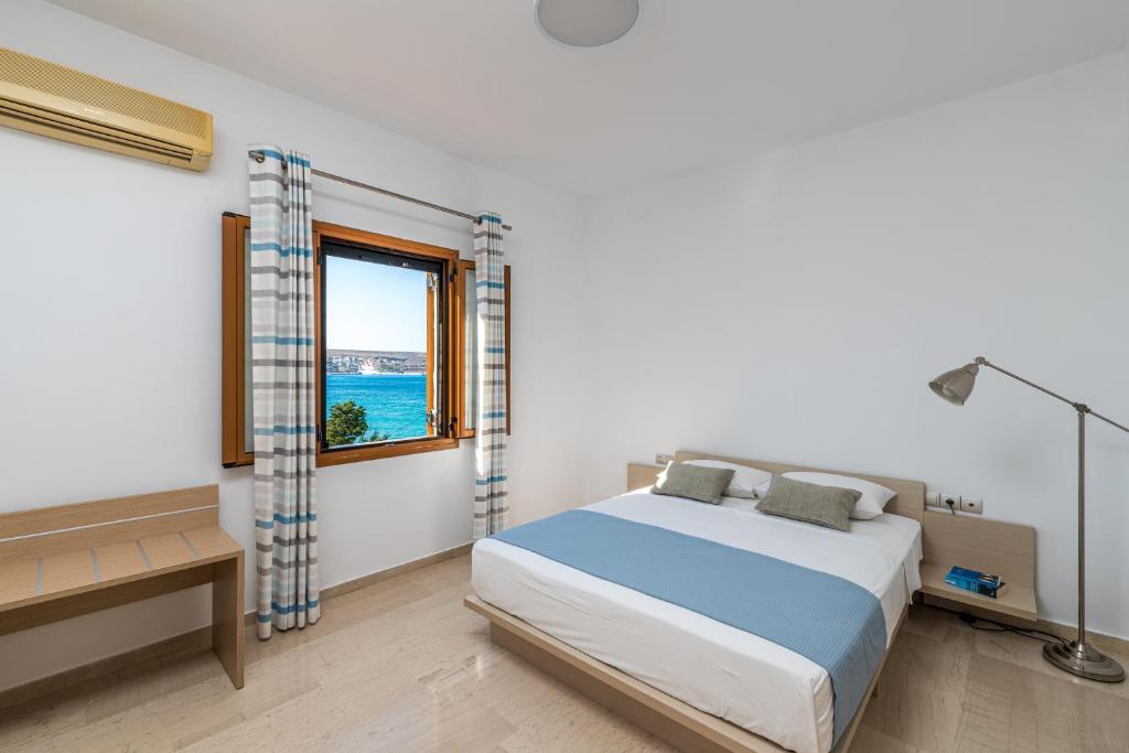 a white bedroom with a bed and a window at Simon Studios and Apartments in Sitia