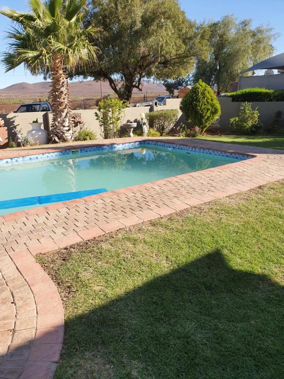 a swimming pool in a yard with a palm tree at KOL-IN SELF CATERING in Prieska