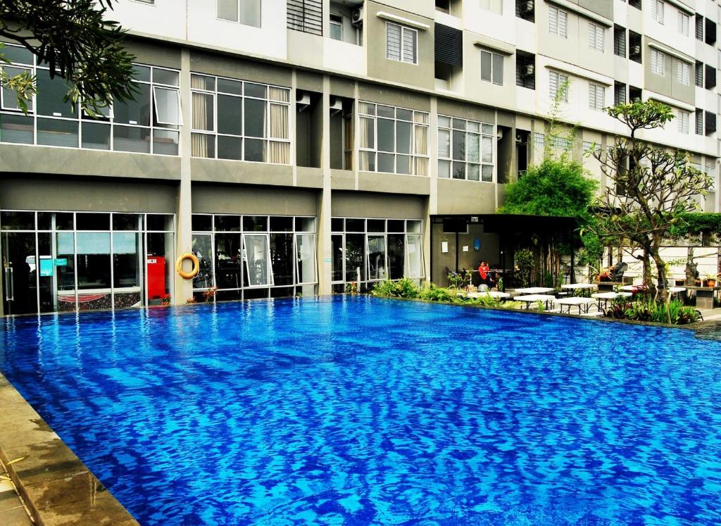 una gran piscina azul frente a un edificio en High Livin Apartment Baros en Cimahi