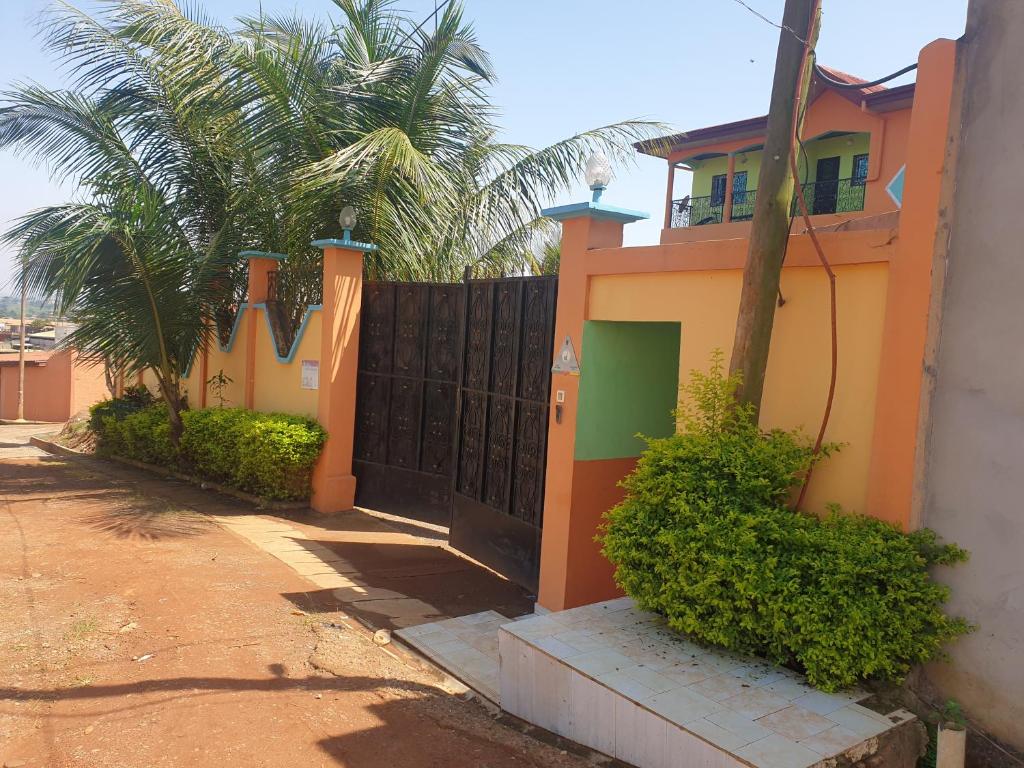 a fence in front of a house with palm trees at Résidence La ROSÉE in Yaoundé