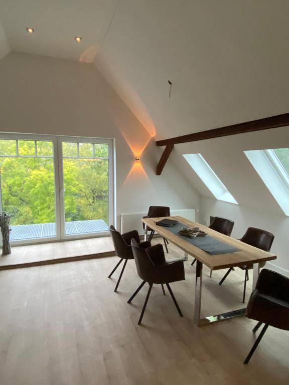 ein Esszimmer mit einem Tisch, Stühlen und Fenstern in der Unterkunft Villa am See in Bad Sachsa