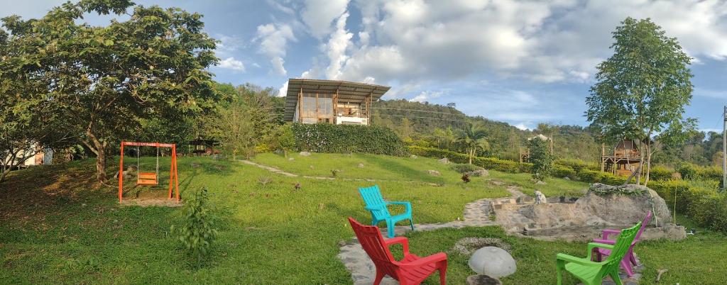un grupo de sillas coloridas sentadas en un campo en VILLA DE LOS ANGELES GLAMPING, en Anolaima