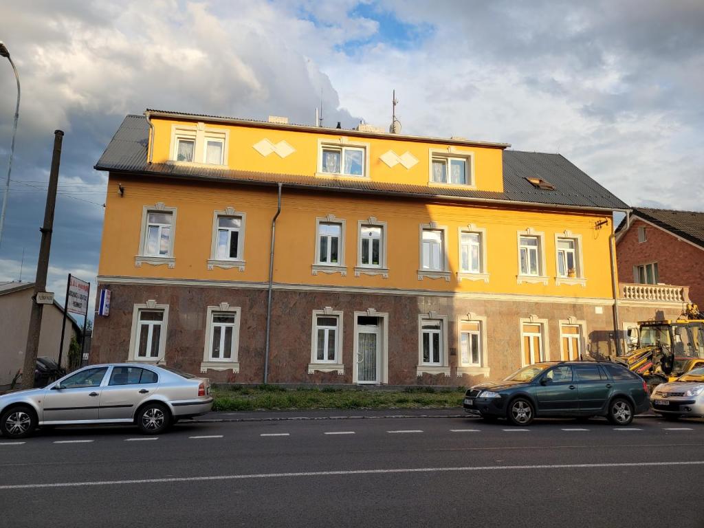 żółty budynek z samochodami zaparkowanymi przed nim w obiekcie Penzion Duong Apartments w Karlowych Warach