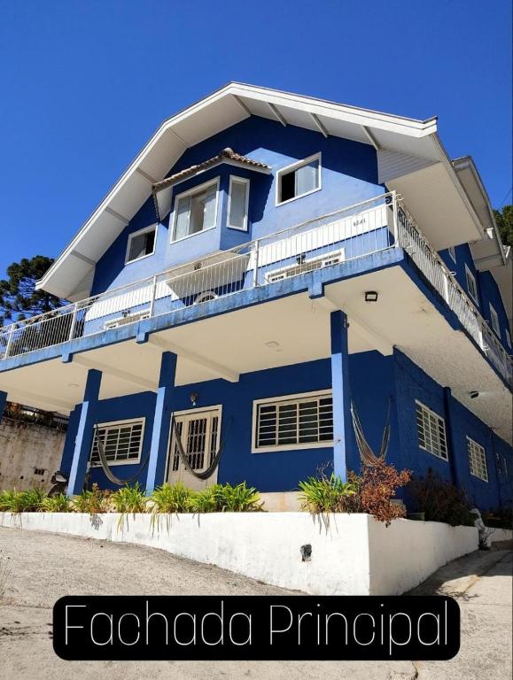 a blue and white building with a balcony at A Nossa Casinha no Bosque - 4min do Parque Capivari in Campos do Jordão
