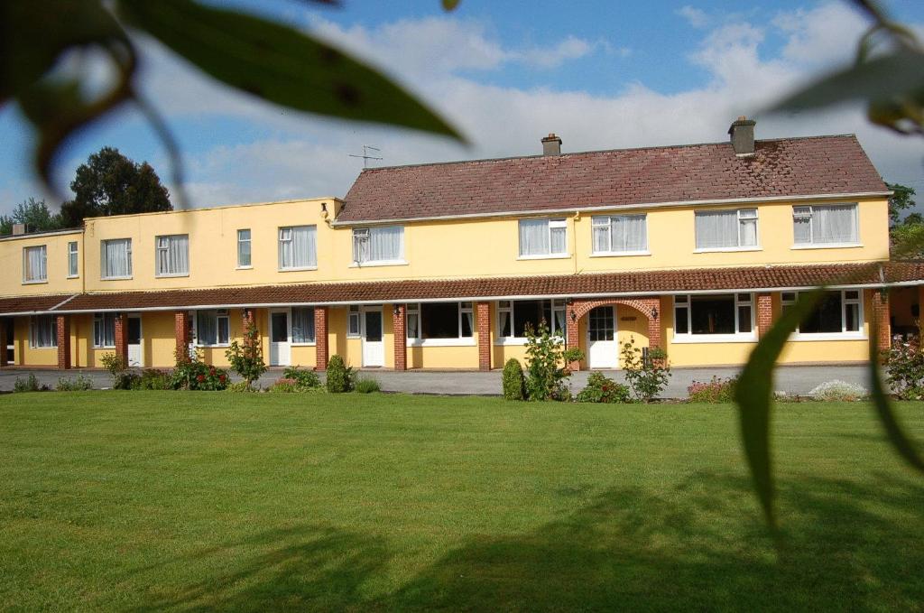 a large yellow building with a large yard at The Gardens guest accommodation in Killarney