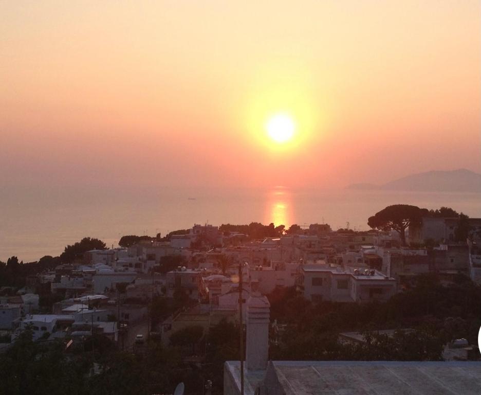 a view of a city with the sun setting over the ocean at Casa Capri Sunset in Anacapri