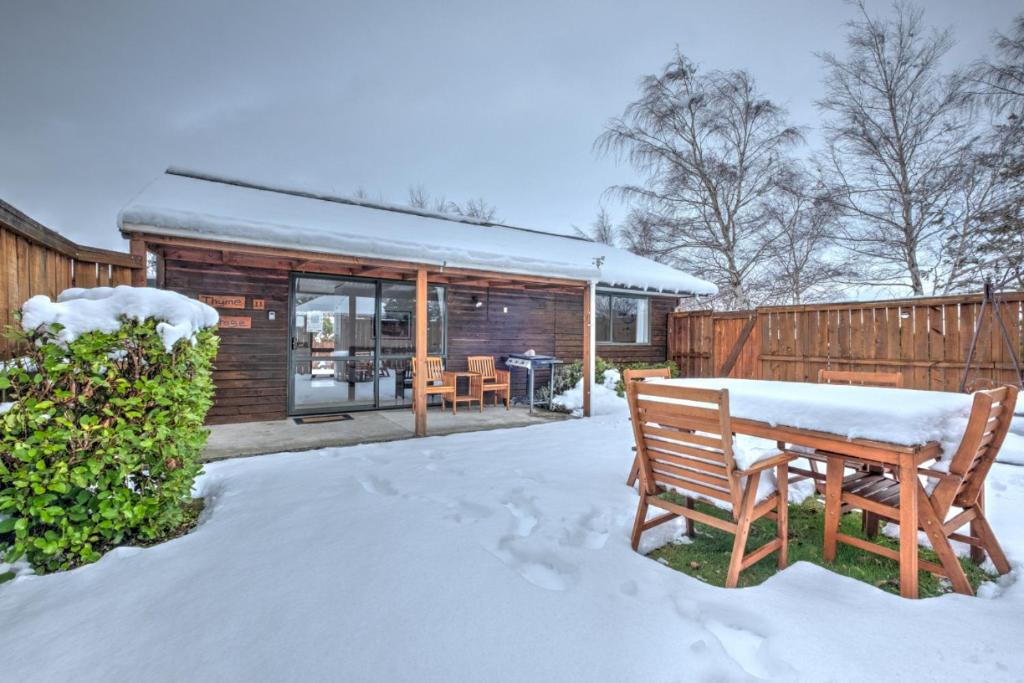 een sneeuwbedekte tuin met een bank en een huis bij 11 Dorset Street in Hanmer Springs
