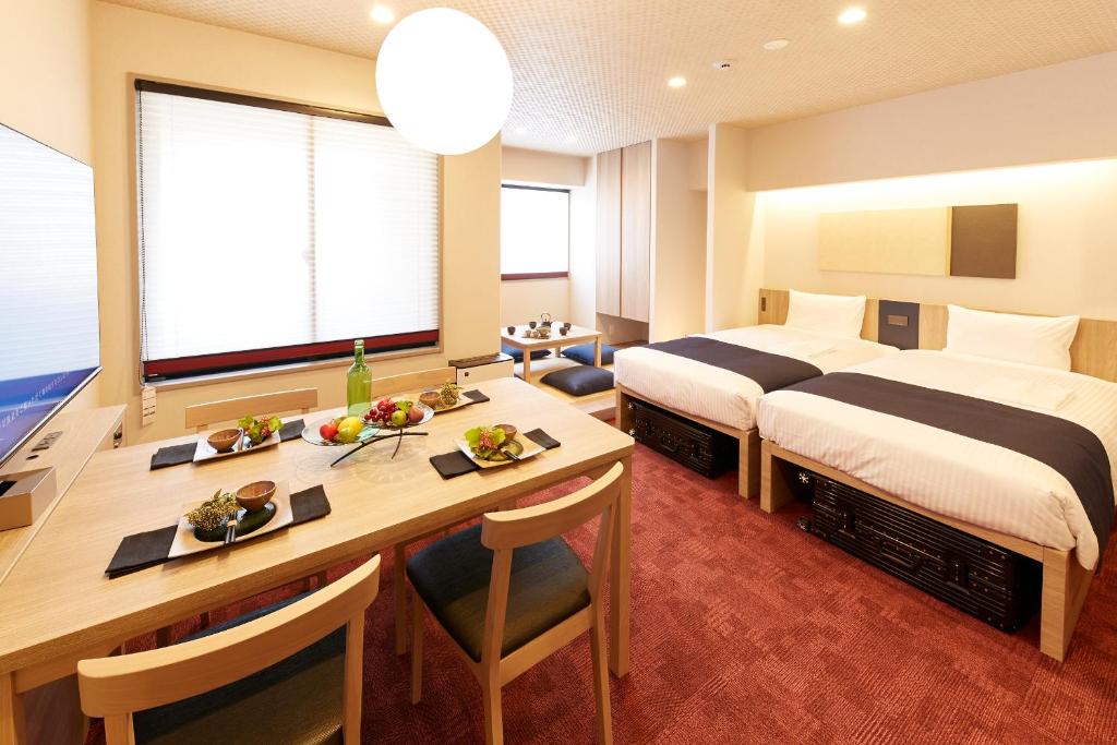 a hotel room with a desk and a bed and a table at MONday Apart Premium KYOTO Station in Kyoto