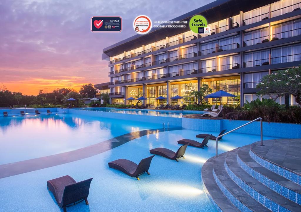 Swiss-Belresort Belitung في Tanjungbinga: مسبح الفندق مع الكراسي امام المبنى