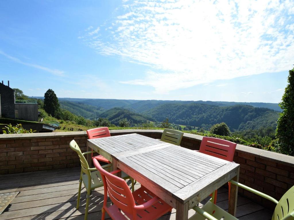 a wooden table and chairs on a deck with a view at Cozy home with view and hottub in Rochehaut