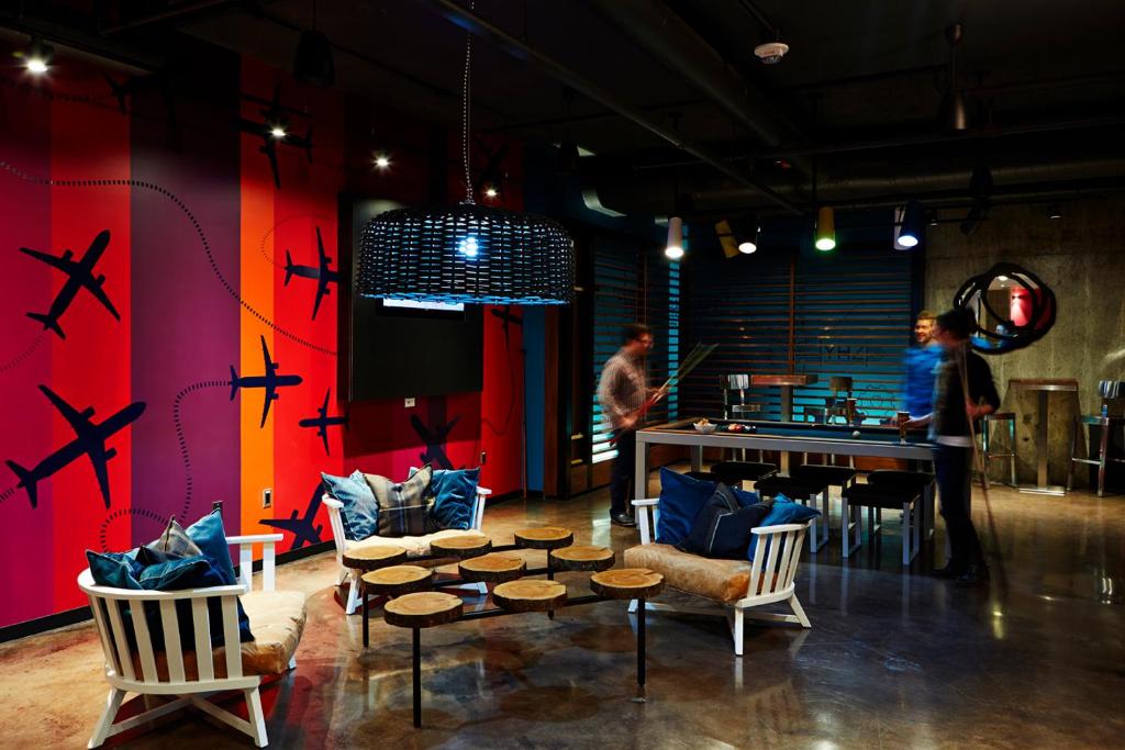 a room with chairs and a table and a room with people at Alt Hotel Halifax Airport in Enfield