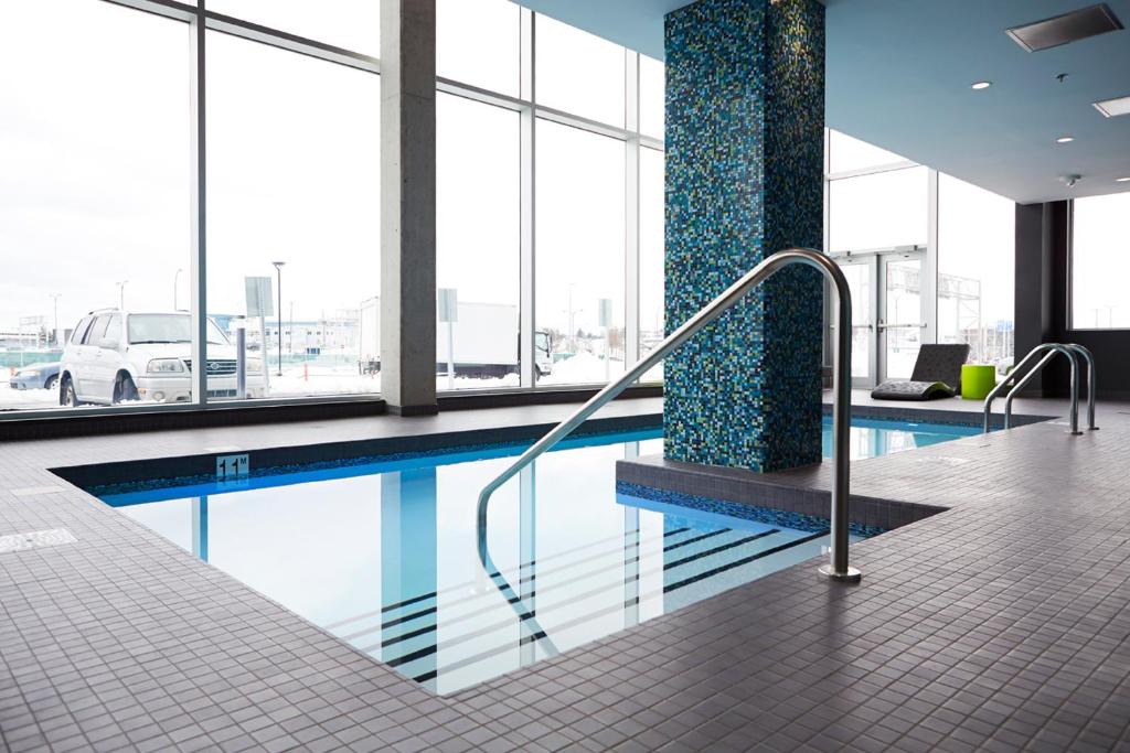 a swimming pool in a building with windows at Alt Hotel Halifax Airport in Enfield