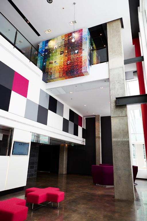 a lobby with red chairs and a flat screen tv at Alt Hotel Halifax Airport in Enfield