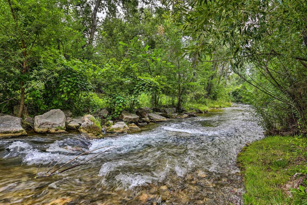 um rio com pedras e árvores ao lado em Central Creekfront Spearfish Apt by City Park em Spearfish