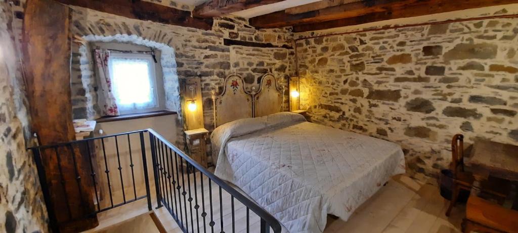 1 dormitorio con 1 cama en una pared de piedra en b&b La Corte dei Cerri- Il Piccolo Chalet en Frassinoro
