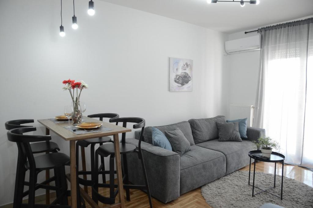 a living room with a couch and a table with chairs at Apartment DobraYa Grey in Novi Sad