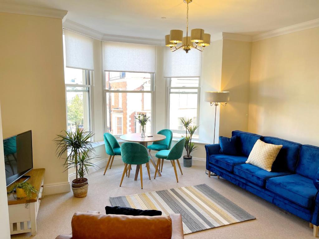 a living room with a blue couch and a table at Stylish apartment with free parking, lift & views in Scarborough