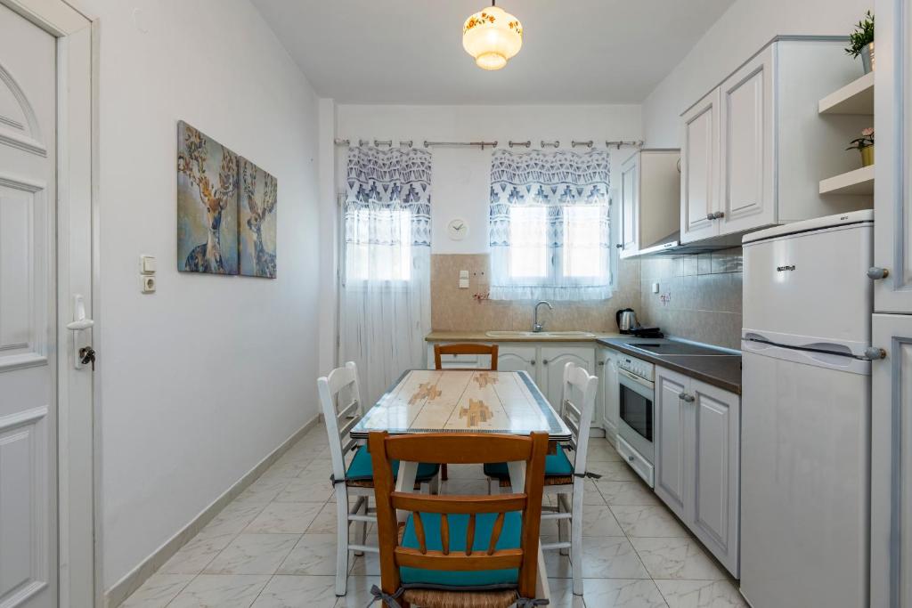 a kitchen with white cabinets and a table and chairs at Stenorimi Valley House - Livadi, Astypalea in Livadi Astypalaias