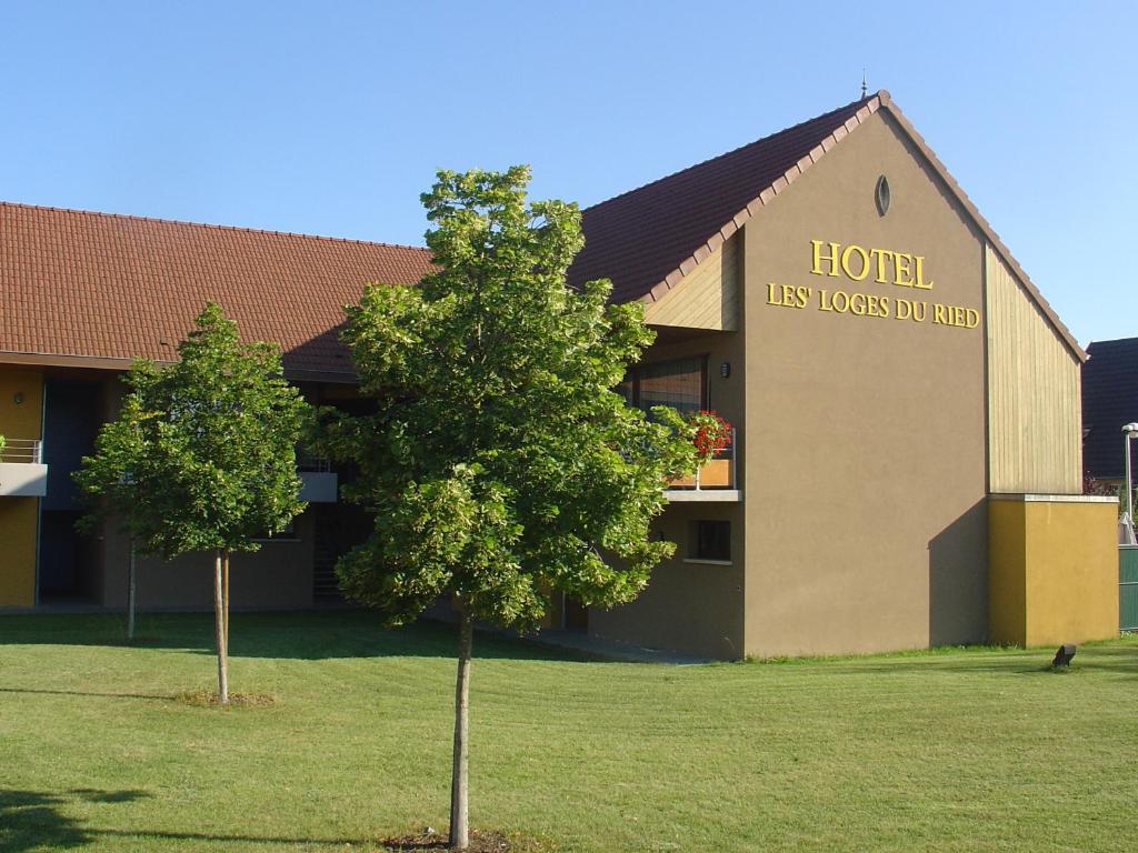 a hotel with a tree in front of a building at Les Loges Du Ried in Marckolsheim
