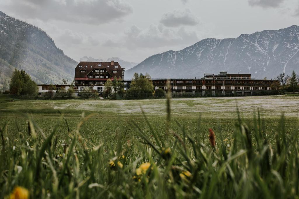 ein großes Gebäude auf einem Feld mit Bergen im Hintergrund in der Unterkunft G'sund & Natur Hotel Die Wasnerin - Adults Only in Bad Aussee