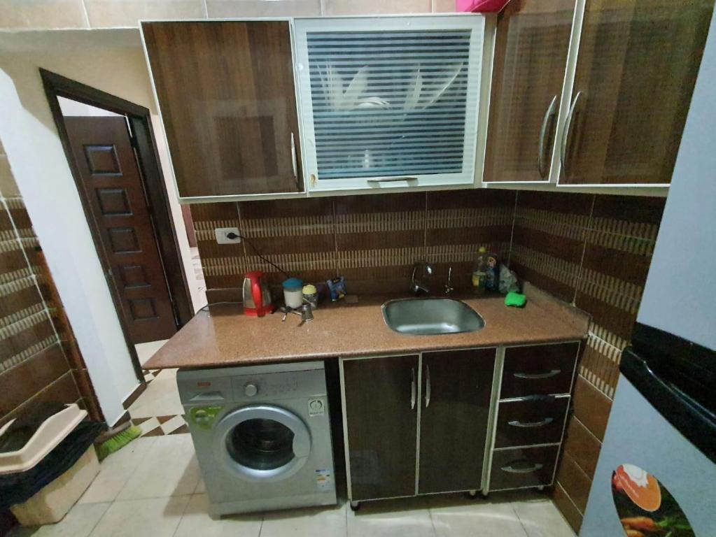 a small kitchen with a sink and a washing machine at Abeer Suites in Hurghada