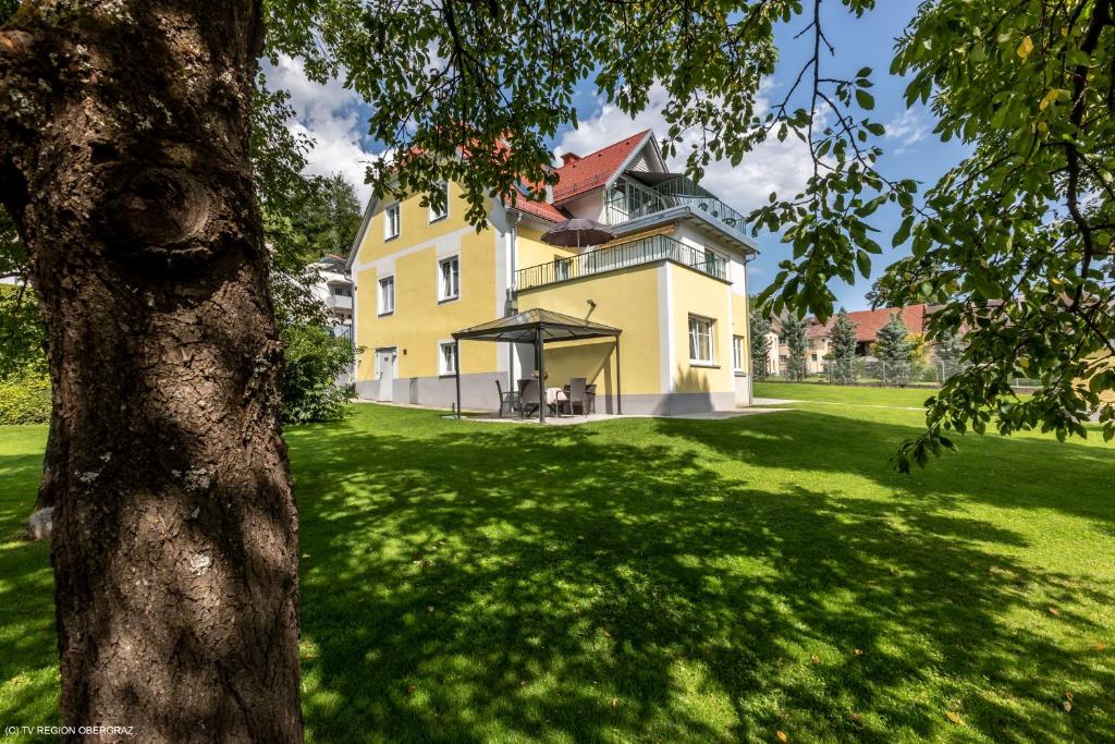 ein großes gelbes Haus auf einem grünen Feld mit einem Baum in der Unterkunft Gästehaus Landgraf in Übelbach