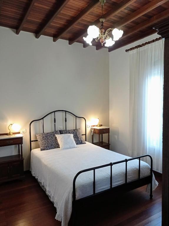 a bedroom with a bed and a window and a chandelier at A Mercé in A Pobra do Caramiñal