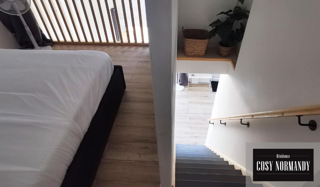 a bedroom with a white bed and a staircase at Cosy Normandy - 03 in Bois-Jérôme-Saint-Ouen