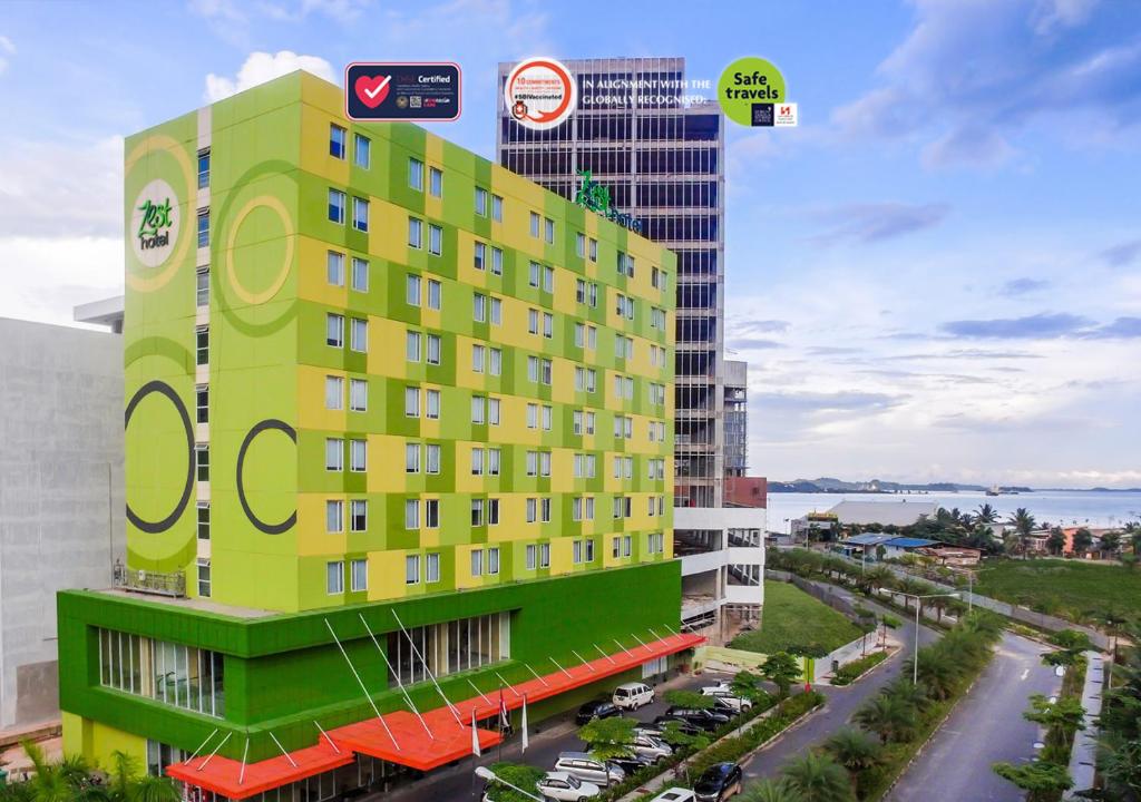 a yellow and green building next to a street at Zest Harbour Bay Batam by Swiss-Belhotel International in Nagoya
