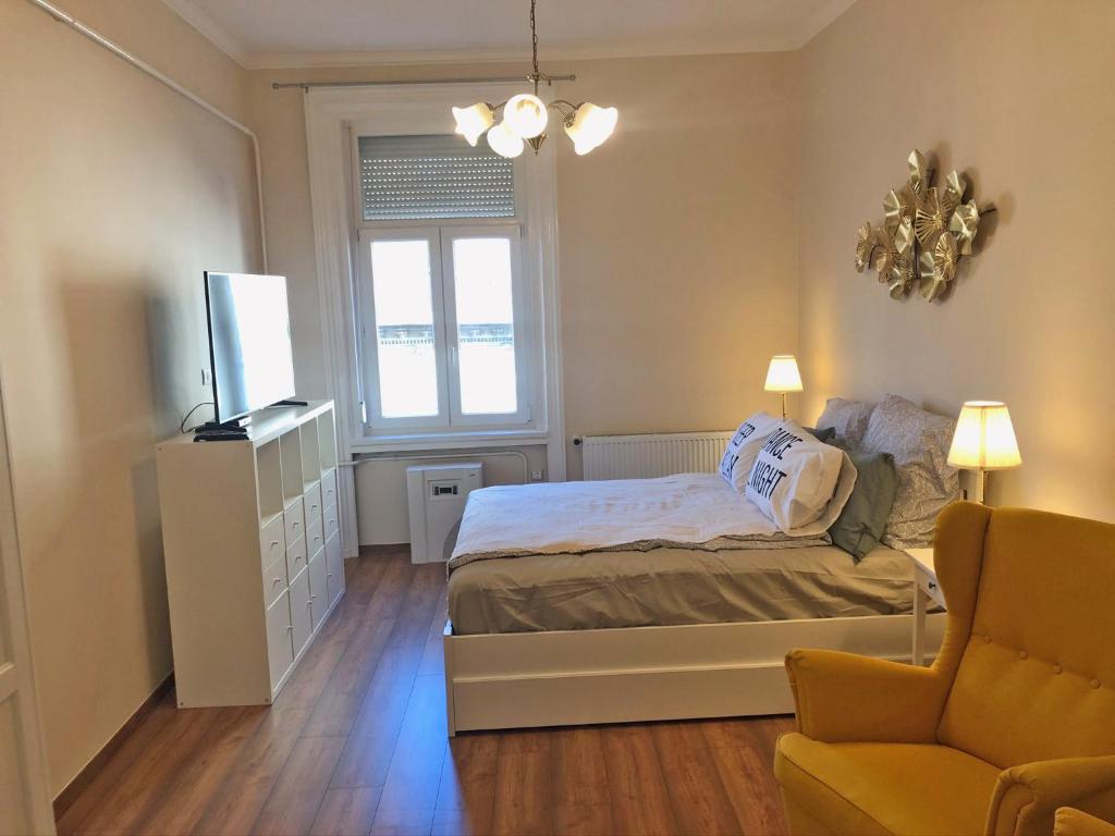 a bedroom with a bed and a television and a chair at Modern comfort in historical Budapest in Budapest