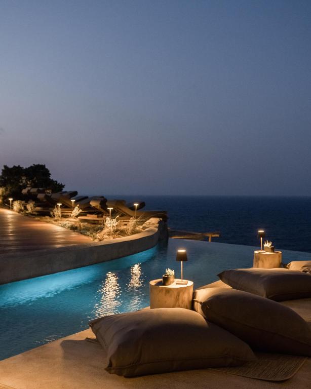 a resort pool with a view of the ocean at night at Acro Suites - A Wellbeing Resort in Agia Pelagia