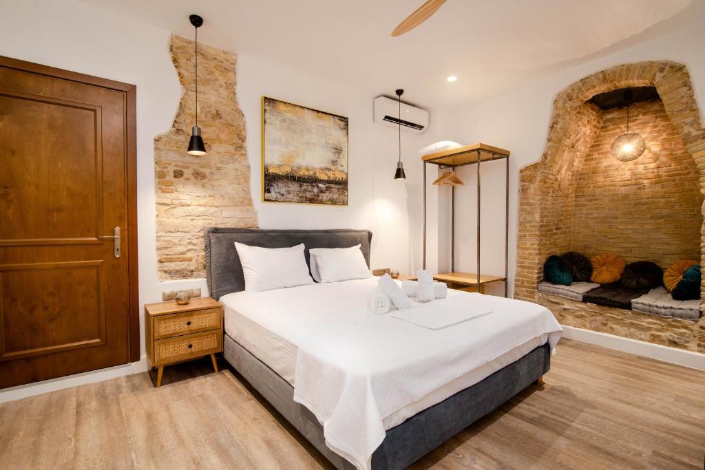 a bedroom with a large white bed and a brick wall at Curcumelli Luxury Suites - ΠΟΡΤΟΝΙ 1 in Corfu