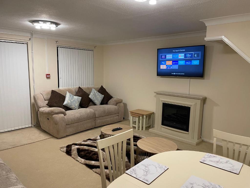 sala de estar con sofá y TV en la pared en Elegant Devon, en Luton